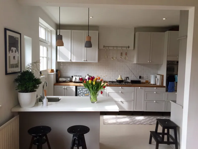 A white shaker kitchen with an oak worktop and breakfast bar, designed and built by South East Build